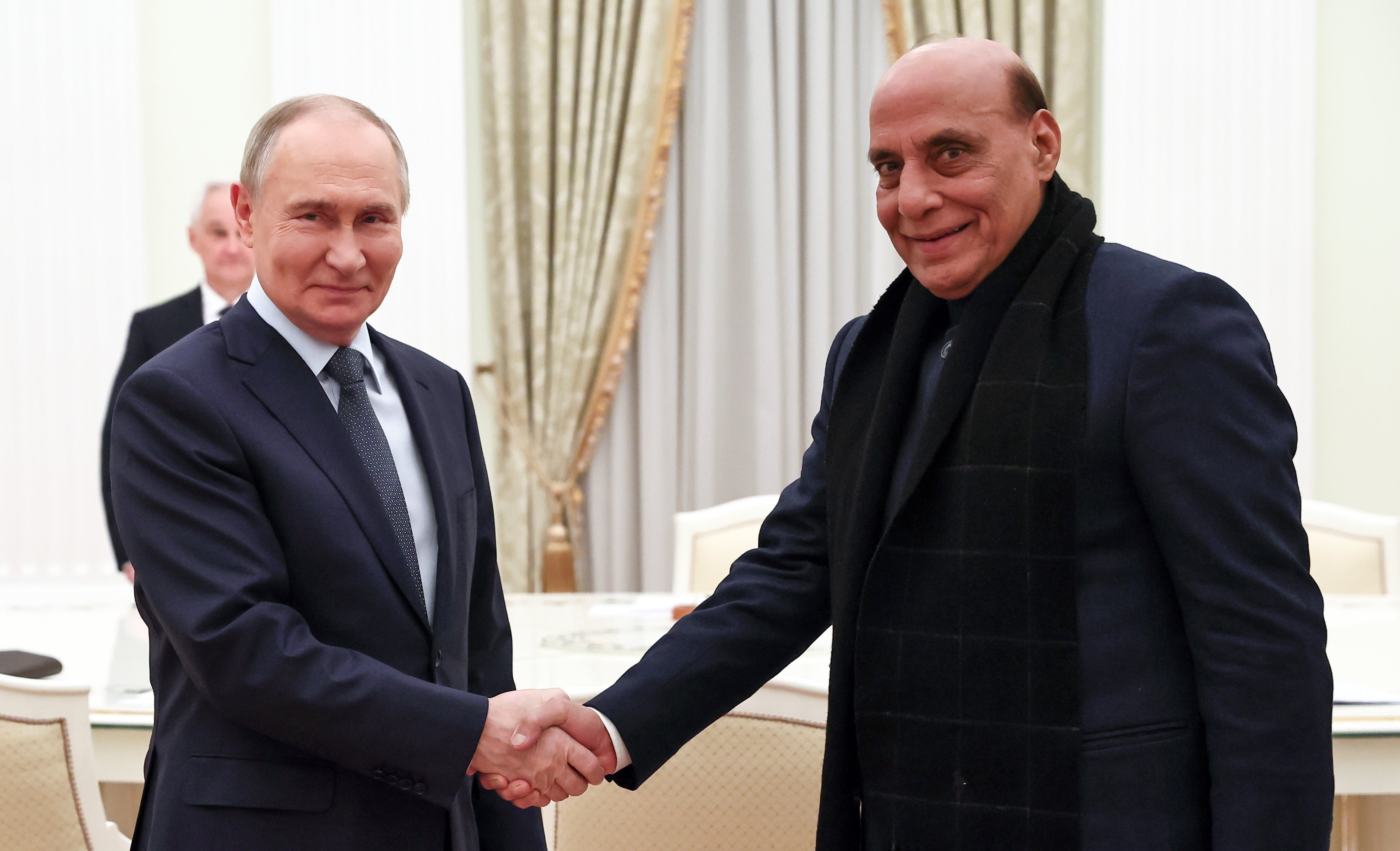 Russian president Vladimir Putin (L) and Indian defence minister Rajnath Singh shake hands