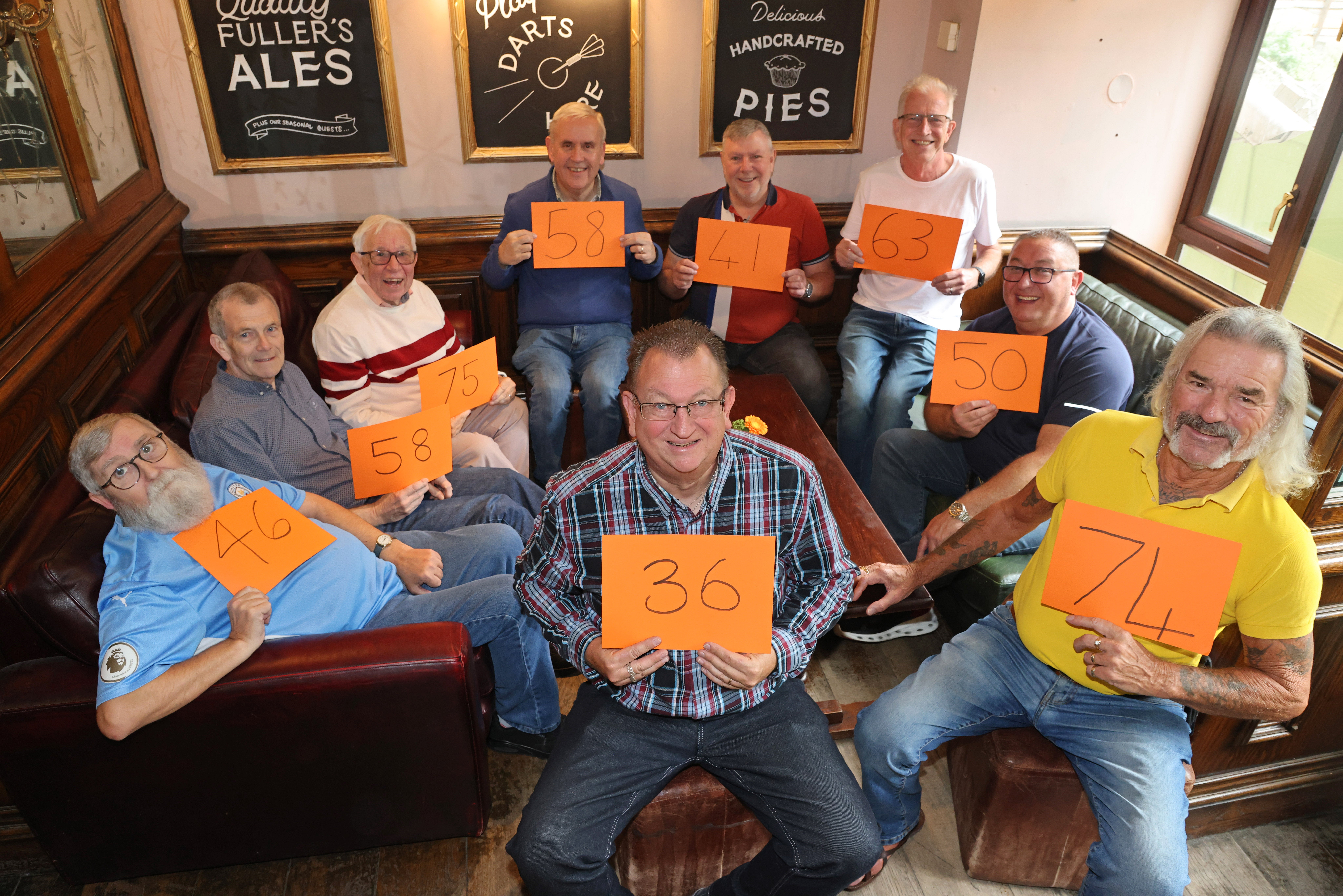 Members of the Men’s VMU holding cards to show what age they were when they were first diagnosed with breast cancer
